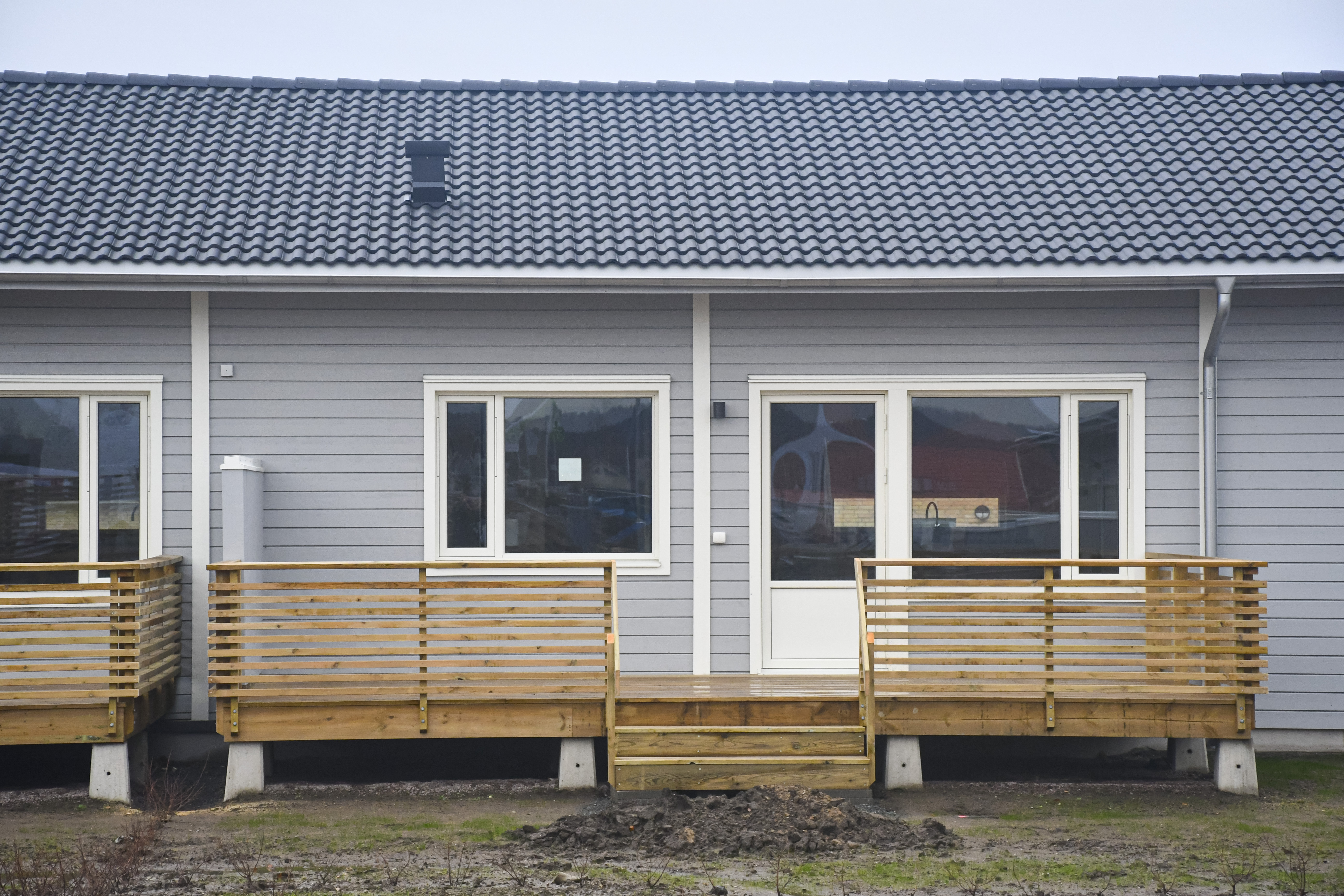 Exteriör bild från Kuylenstjerna. Ljusgråa marklägenheter med utplatser på baksidan och veranda med förråd på framsidan