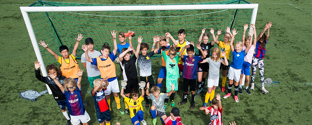 Glada barn framför ett fotbollsmål