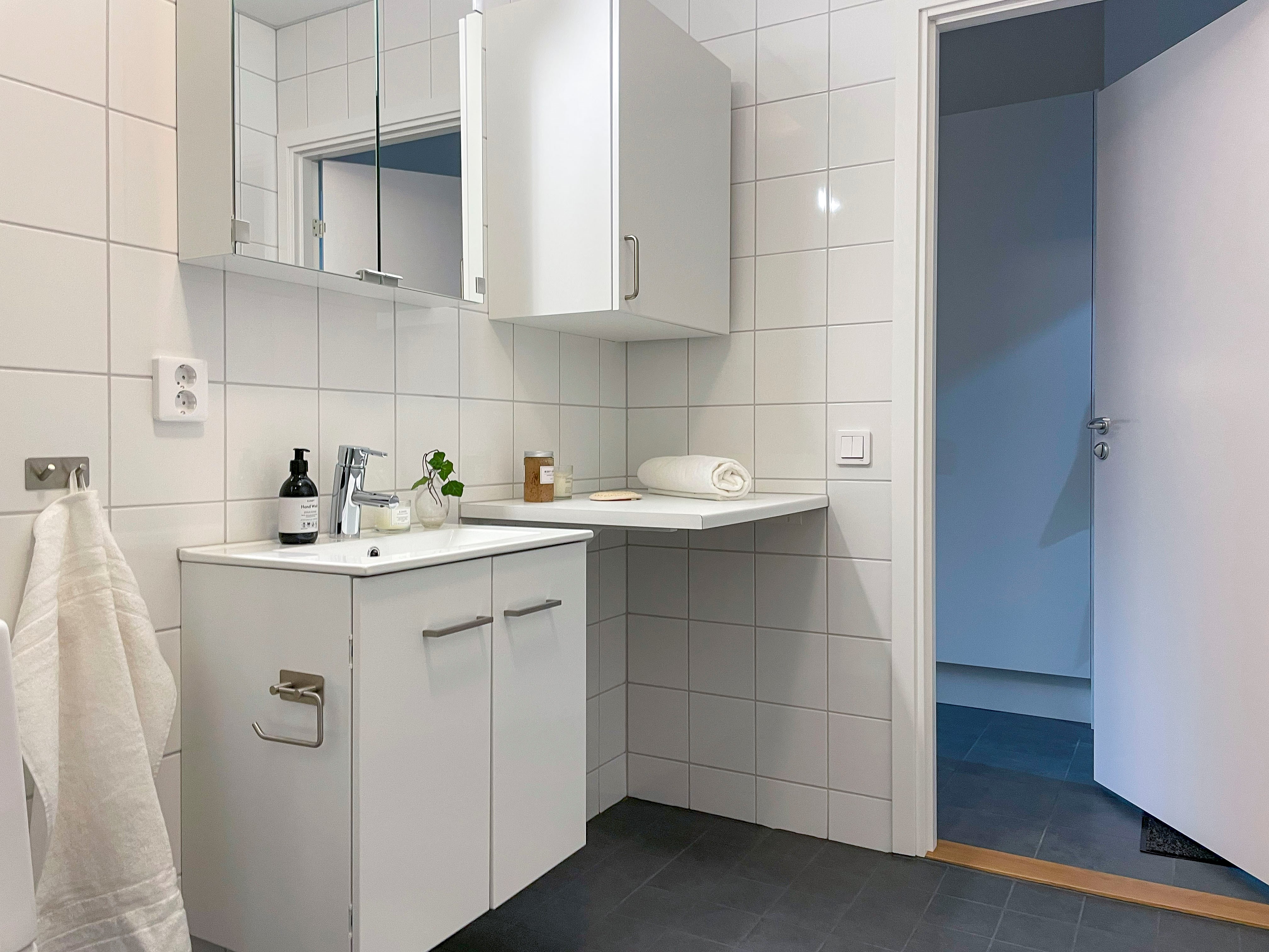 Bild från badrum, visar handfat, badrumsskåp och toaletten